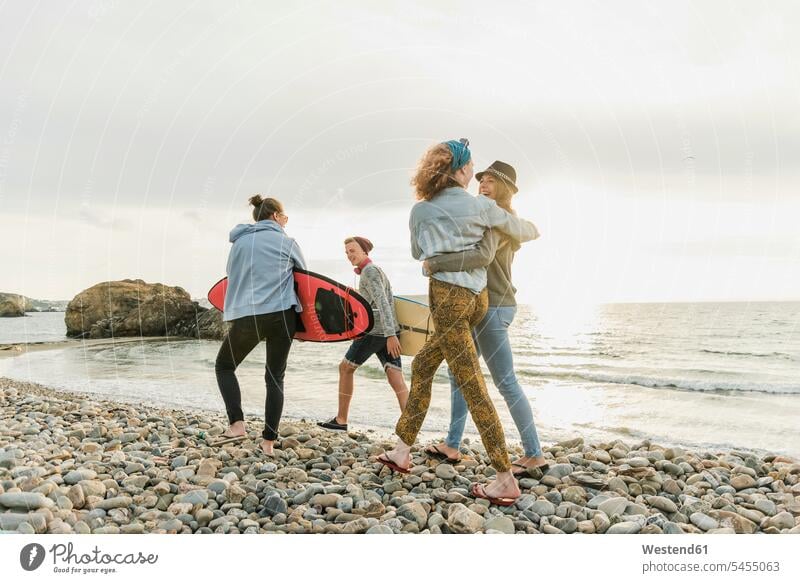 Glückliche Freunde mit Surfbrettern am steinigen Strand glücklich glücklich sein glücklichsein Beach Straende Strände Beaches surfboard surfboards Surfer
