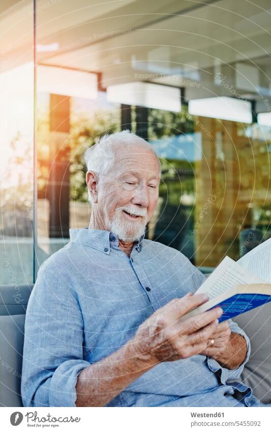 Älterer Mann sitzt auf der Terrasse und liest Buch Senior Rentner lesen sitzen Senioren Erwachsener Mensch schmunzeln Alter Zuversicht Komfortabel Entspannung