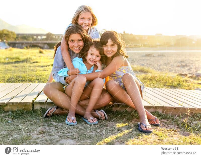 Gruppenbild von vier Mädchen, die im Sommer auf der Strandpromenade sitzen weiblich Freundinnen Gruppenaufnahme Gruppenfoto Kind Kinder Kids Mensch Menschen