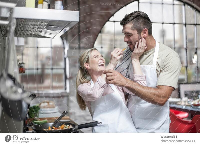 Ein Paar kocht zusammen und hat Spaß in der Küche Spass Späße spassig Spässe spaßig kochen lachen Pärchen Paare Partnerschaft essen essend positiv Emotion