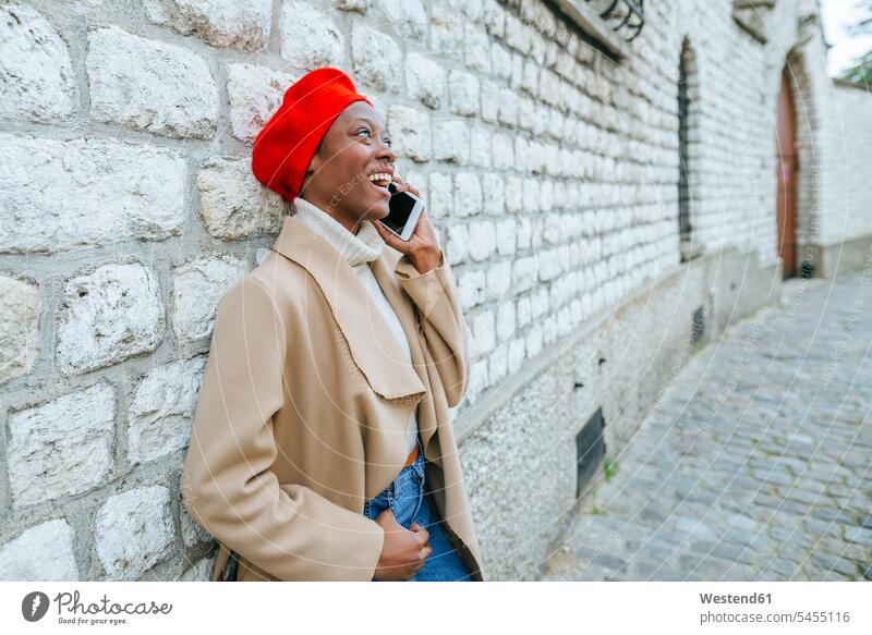 Junge Frau in Paris lehnt an Wand und telefoniert weiblich Frauen Smartphone iPhone Smartphones telefonieren anrufen Anruf telephonieren lächeln alleinreisend