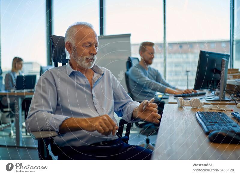 Leitender Geschäftsmann am Schreibtisch sitzend im Büro Businessmann Businessmänner Geschäftsmänner Senior ältere Männer älterer Mann Senioren arbeiten Arbeit
