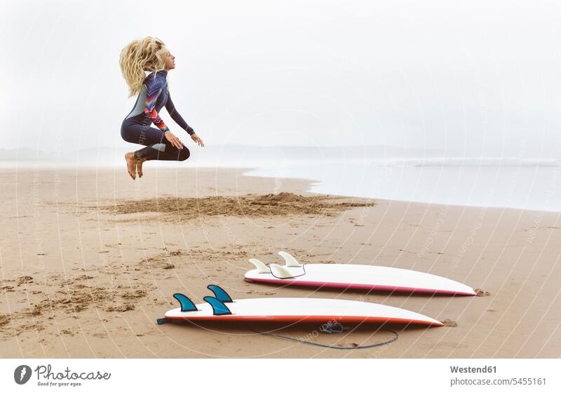 Spanien, Aviles, junger Surfer, der sich vor dem Surfen aufwärmt Surfbrett Surfbretter surfboard surfboards Surferin Wellenreiterinnen Surferinnen Strand Beach