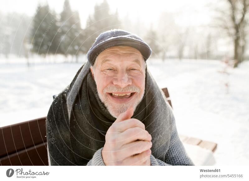 Porträt eines glücklichen älteren Mannes, der auf einer Bank in einer Winterlandschaft sitzt Wald Forst Wälder lachen Senior ältere Männer älterer Mann Senioren