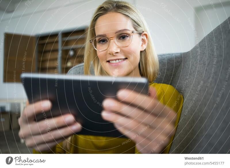 Porträt einer lächelnden Frau mit Brille, die mit einem Mini-Tablett auf der Couch sitzt Tablet Computer Tablet-PC Tablet PC iPad Tablet-Computer Portrait
