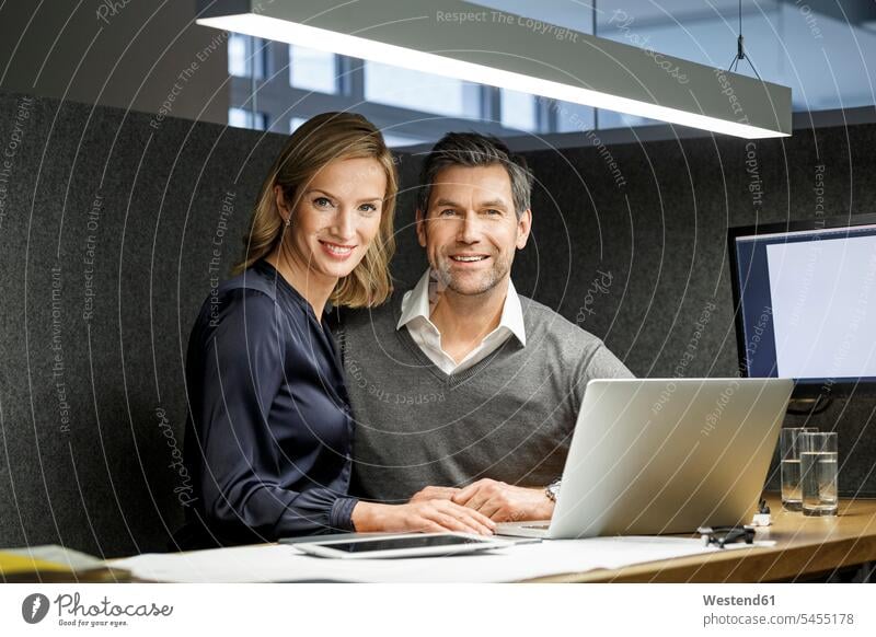 Porträt einer lächelnden Geschäftsfrau und eines Geschäftsmannes mit Laptop in einer Besprechungskiste Notebook Laptops Notebooks Büro Office Büros