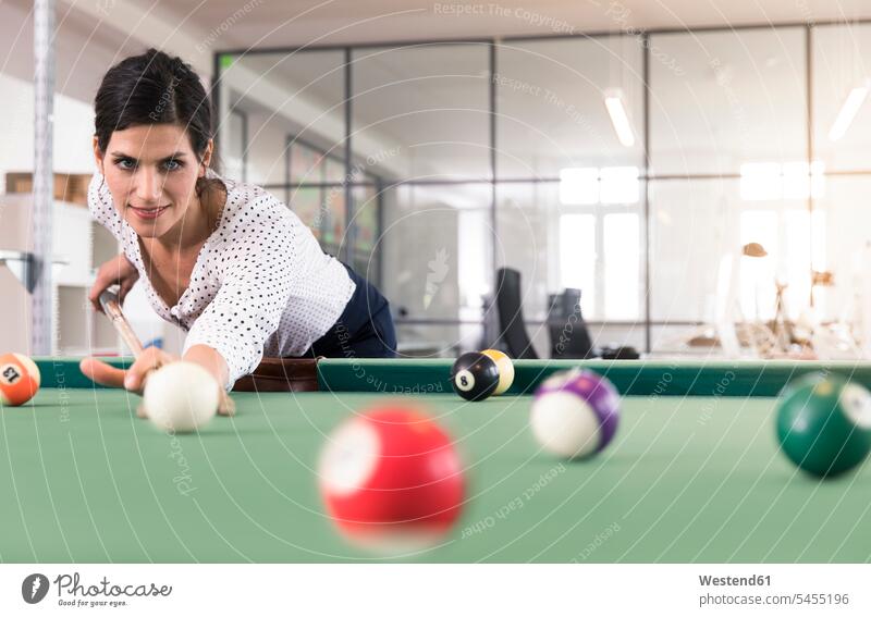 Entschlossene Geschäftsfrau spielt Pool-Billard in einem modernen Büro Billardspiel Billardtisch Billardtische spielen zielstrebig Zielstrebigkeit Office Büros