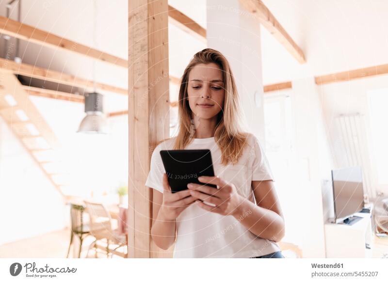 Junge Frau zu Hause mit digitalem Tablett weiblich Frauen Zuhause daheim lesen Lektüre stehen stehend steht Planung Pläne planen Tablet Computer Tablet-PC