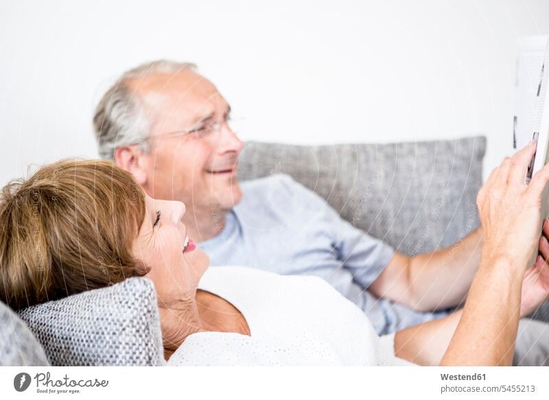 Älteres Ehepaar zu Hause auf der Couch liegend mit digitalem Tablett Tablet Computer Tablet-PC Tablet PC iPad Tablet-Computer liegt entspannt entspanntheit