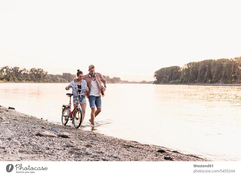 Junges Paar mit Fahrrad watend im Fluss gehen gehend geht Pärchen Paare Partnerschaft Mensch Menschen Leute People Personen Fluesse Fluß Flüsse Gewässer Wasser