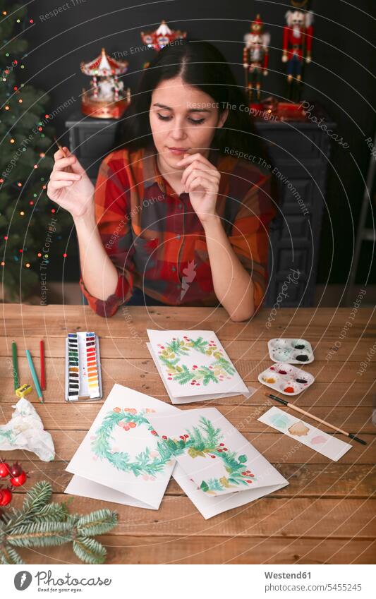 Junge Frau malt Weihnachtskarte mit Aquarellfarben weiblich Frauen Portrait Porträts Portraits Weihnachtskarten Erwachsener erwachsen Mensch Menschen Leute