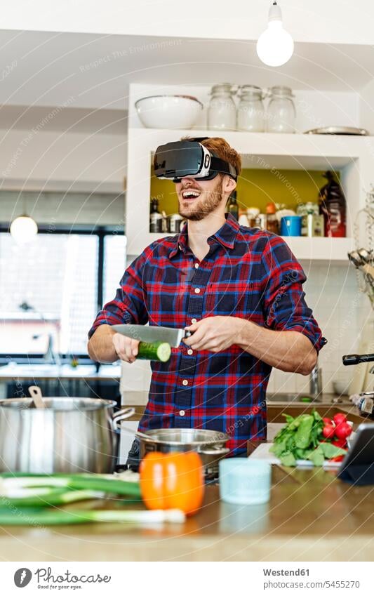Glücklicher junger Mann mit VR-Brille beim Kochen in der Küche kochen Virtuelle Realität Virtuelle Realitaet glücklich glücklich sein glücklichsein Brillen
