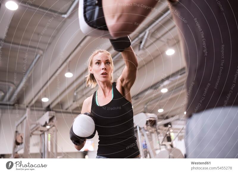 Junge Frau boxt mit ihrem Trainer Uebungsleiter Übungsleiter Frauenboxen Training trainieren Boxerin Boxerinnen schlagen Schlag Boxen Boxsport Boxkampf