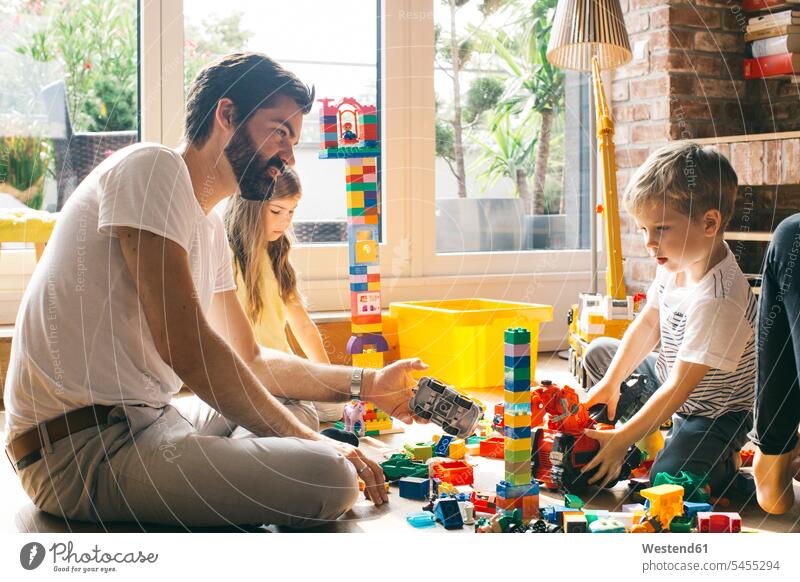Familie spielt gemeinsam mit Bausteinen auf dem Boden Bauklotz spielen Familien Mensch Menschen Leute People Personen Zuhause zu Hause daheim Geschicklichkeit