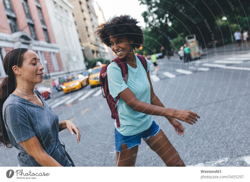 USA, New York City, zwei Freunde überqueren die Straße Strassen Straßen Freundinnen Freundschaft Kameradschaft Frau weiblich Frauen lächeln gehen gehend geht