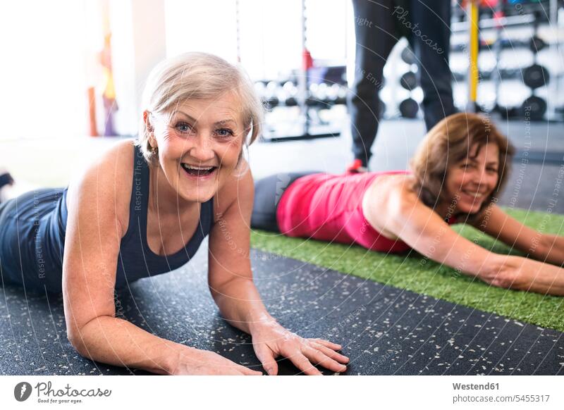Zwei fittere ältere Frauen haben Spaß im Fitnessstudio lachen trainieren Seniorin Seniorinnen alt Fitnessclubs Fitnessstudios Turnhalle positiv Emotion Gefühl