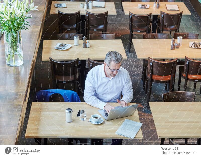 Reifer Geschäftsmann im Café mit Laptop Cafe Kaffeehaus Bistro Cafes Cafés Kaffeehäuser arbeiten Arbeit Businessmann Businessmänner Geschäftsmänner Notebook
