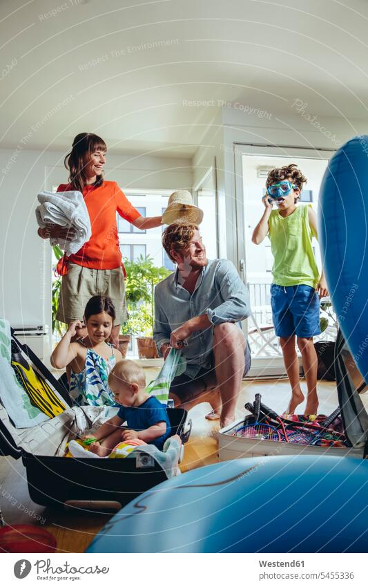 Glückliche fünfköpfige Familie packt für Urlaubsreise Spaß Spass Späße spassig Spässe spaßig packen einpacken Familien glücklich glücklich sein glücklichsein