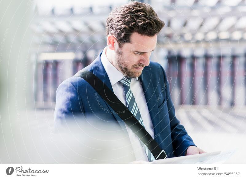 Geschäftsmann steht auf Parkdeck und liest auf digitalem Tablet Dokument Dokumente Papiere Unterlagen Parkdecks lesen Lektüre arbeiten Arbeit Tablet Computer