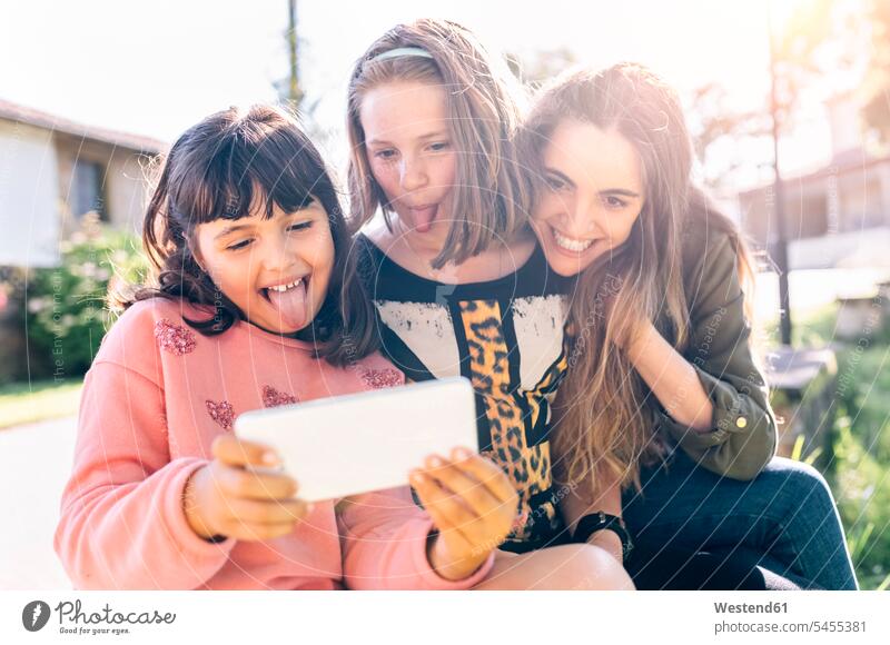 Drei verspielte Mädchen machen ein Selfie im Freien Schwester Schwestern Portrait Porträts Portraits Selfies Spaß Spass Späße spassig Spässe spaßig Handy
