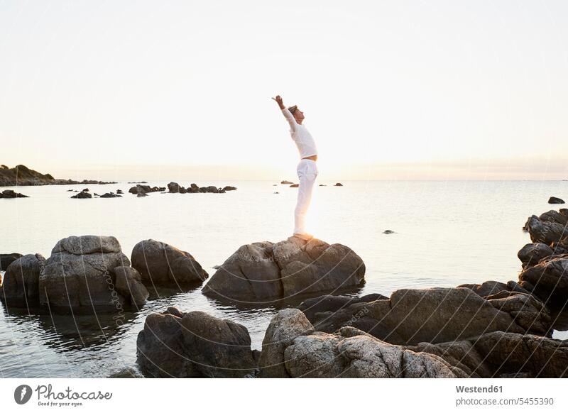 Reifer Mann macht Yoga-Übungen auf einem Felsen am Meer Männer männlich Yogauebungen Yogaübungen Jogauebung Jogauebungen Meere Erwachsener erwachsen Mensch