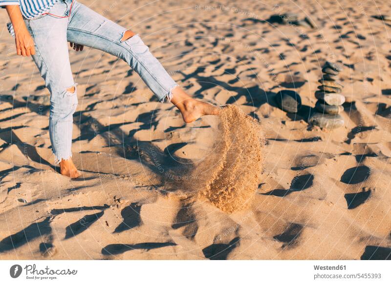 Frau steht auf einem Bein und wirft Sand an den Strand, Teilansicht stehen stehend sandig auf einem Bein stehen Beine Beach Straende Strände Beaches werfen Wurf