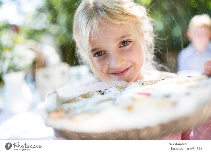 Porträt eines lächelnden Mädchens, das eine Torte im Freien hält weiblich Kuchen Kind Kinder Kids Mensch Menschen Leute People Personen Süßspeise Süsses Süßes
