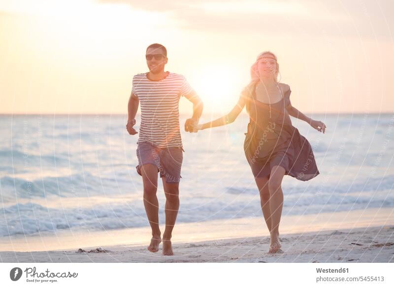 Junges Paar rennt am Strand und hält sich an den Händen Urlaub Ferien Beach Straende Strände Beaches laufen rennen Meer Meere glücklich Glück glücklich sein