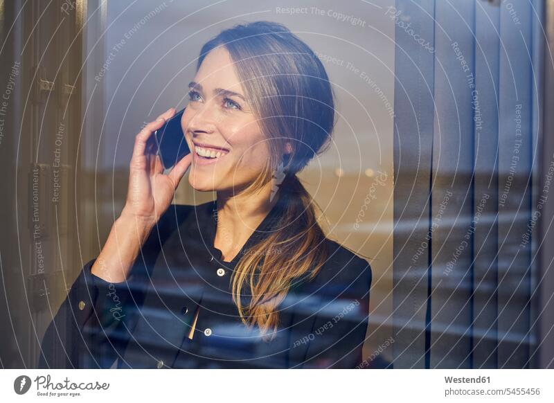 Porträt einer lachenden Geschäftsfrau am Telefon hinter einer Fensterscheibe telefonieren anrufen Anruf telephonieren Portrait Porträts Portraits