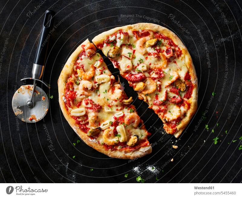 Aufgeschnittene Pizza mit Frutti di mare auf dunklem Boden Food and Drink Lebensmittel Essen und Trinken Nahrungsmittel zubereitet servierfertig angerichtet