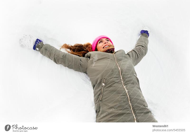 Junge Frau macht einen Schneeengel lachen Winter winterlich Winterzeit positiv Emotion Gefühl Empfindung Emotionen Gefühle fühlen Empfindungen emotional