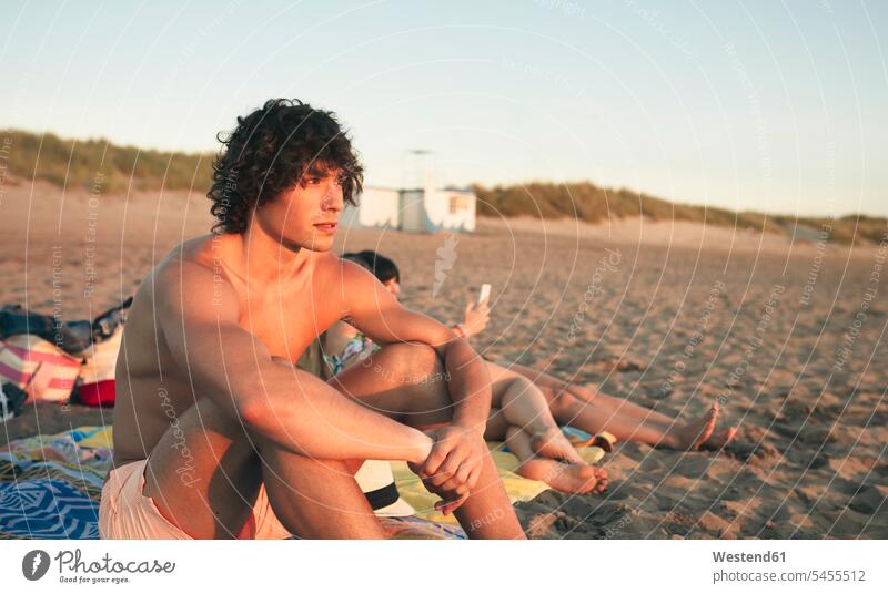 Junger Mann entspannt sich am Strand Männer männlich entspanntheit relaxt Beach Straende Strände Beaches Erwachsener erwachsen Mensch Menschen Leute People