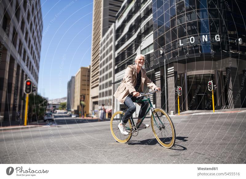 Älterer Mann fährt Fahrrad in der Stadt lächeln staedtisch städtisch Bikes Fahrräder Räder Rad unterwegs auf Achse in Bewegung radfahren fahrradfahren radeln