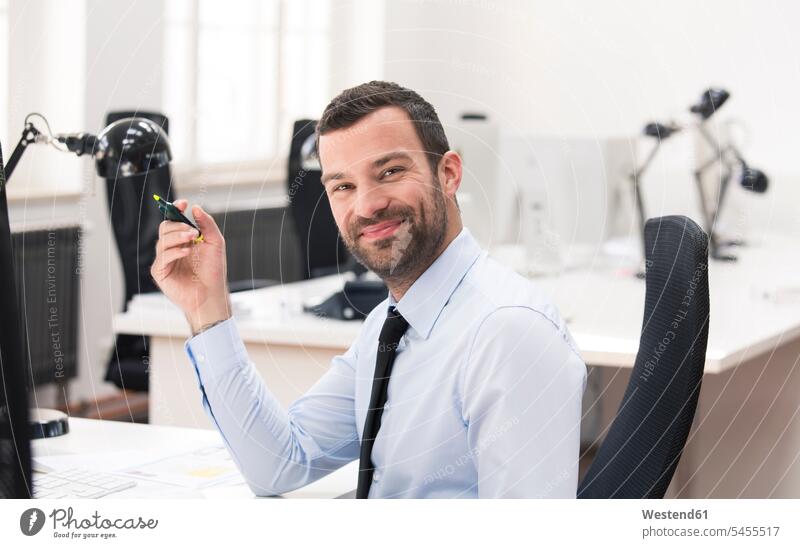 Geschäftsmann mit gelber Markierung schaut in die Kamera arbeiten Arbeit lächeln sitzen sitzend sitzt Businessmann Businessmänner Geschäftsmänner Blickkontakt