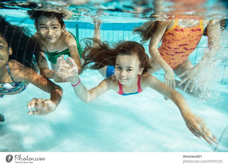 Porträt von glücklichen Kindern, die im Schwimmbad unter Wasser schwimmen Schwimmbaeder Schwimmbäder Glück glücklich sein glücklichsein Kids Unterwasser