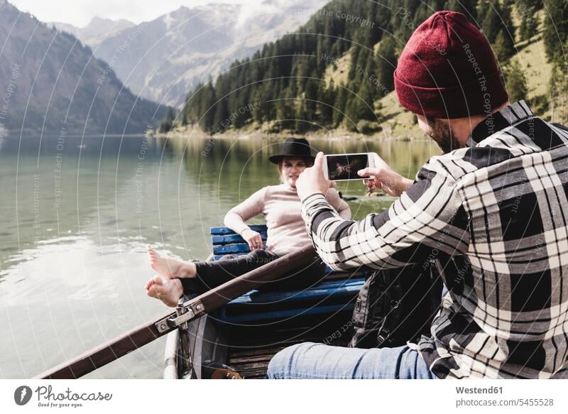 Österreich, Tirol, Alpen, Mann macht Handyfoto von Frau im Ruderboot auf Bergsee See Seen Boot Boote Mobiltelefon Handies Handys Mobiltelefone fotografieren