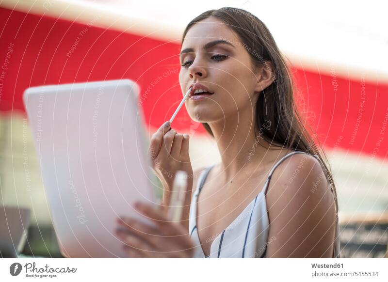 Junge Frau, die Lipgloss aufträgt und eine digitale Tablette hält weiblich Frauen Erwachsener erwachsen Mensch Menschen Leute People Personen Europäer Kaukasier