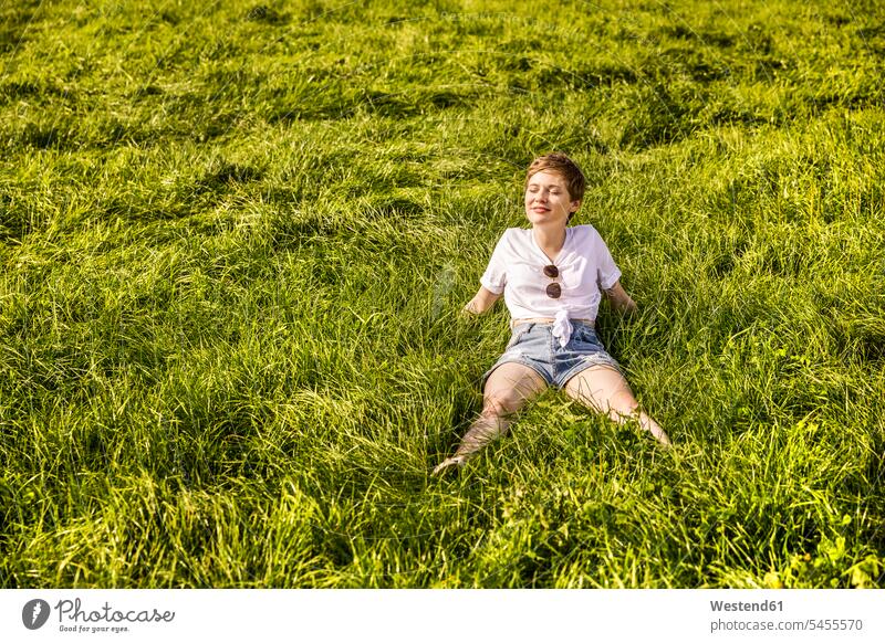 Frau im Feld genießt Sonnenlicht ländlich auf dem Land auf dem Lande Landschaft Landschaften entspannt entspanntheit relaxt lächeln Wiese Wiesen weiblich Frauen