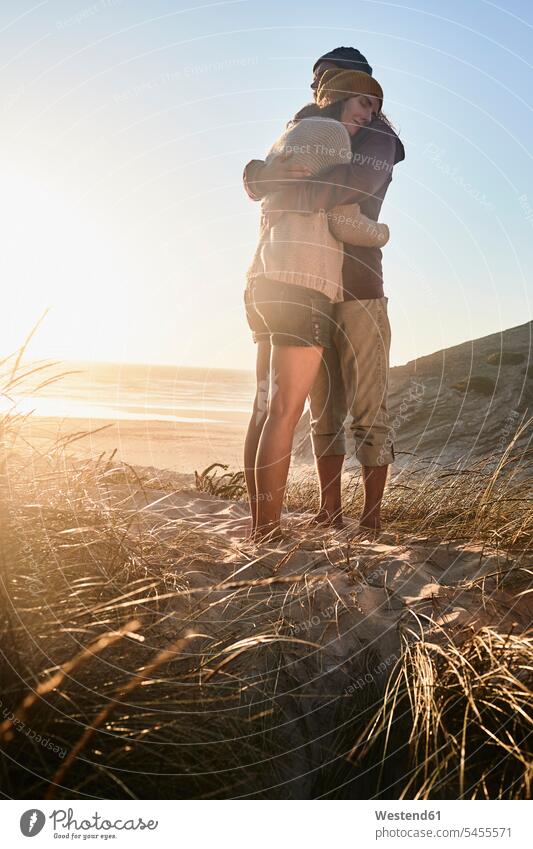Portugal, Algarve, Paar umarmt sich bei Sonnenuntergang am Strand Beach Straende Strände Beaches Pärchen Paare Partnerschaft umarmen Umarmung Umarmungen