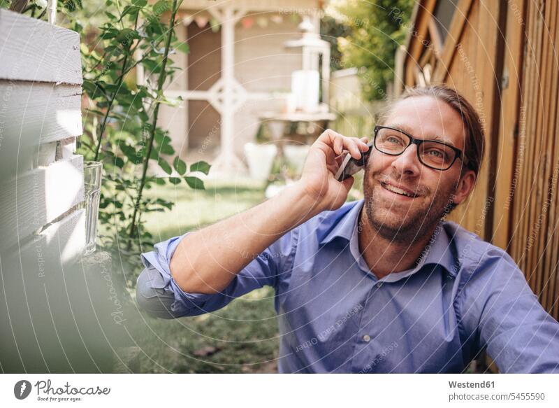 Mann am Telefon im Garten Gärten Gaerten Männer männlich telefonieren anrufen Anruf telephonieren lächeln entspannt entspanntheit relaxt Handy Mobiltelefon