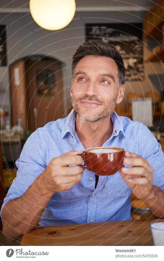 Porträt eines lächelnden Mannes mit einer Tasse Kaffee in einem Kaffeehaus Männer männlich Kaffeetasse Kaffeetassen Portrait Porträts Portraits Cafe Bistro