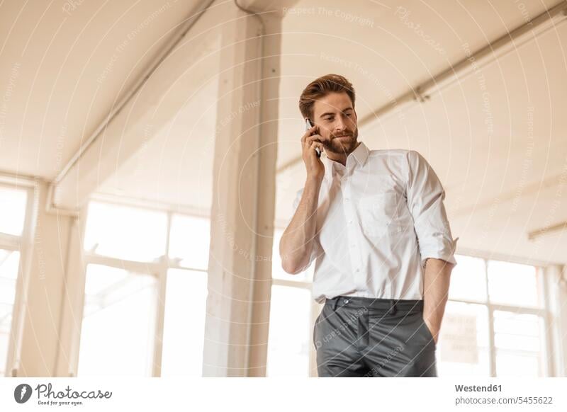 Porträt eines jungen Geschäftsmannes am Telefon in einem Loft telefonieren anrufen Anruf telephonieren Businessmann Businessmänner Geschäftsmänner