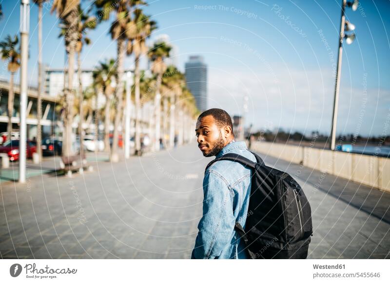 Spanien, Barcelona, junger Mann mit Rucksack beim Spaziergang an der Strandpromenade Rucksäcke Strandpromenaden Männer männlich Promenade Promenaden Erwachsener