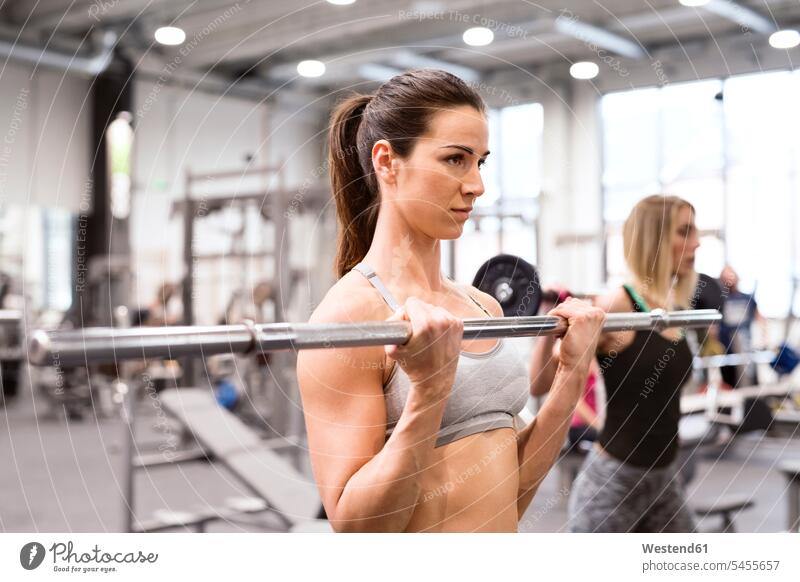 Junge Frau beim Gewichtheben im Fitnessstudio Fitnessclubs Fitnessstudios Turnhalle junge Frau junge Frauen trainieren sportlich fit Gesundheit gesund Sport