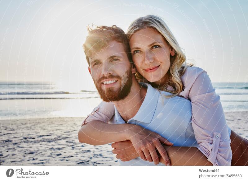 Porträt eines glücklichen Paares am Strand Glück glücklich sein glücklichsein Huckepack lächeln Beach Straende Strände Beaches Pärchen Partnerschaft Mensch