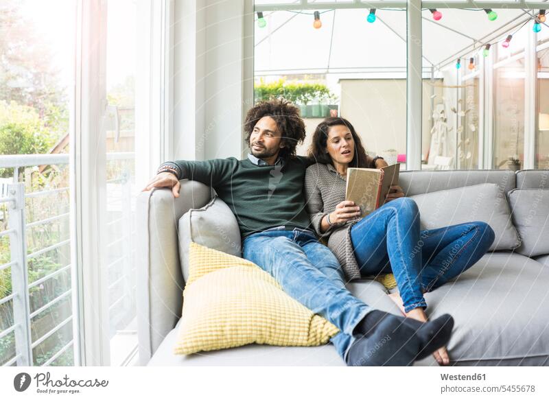 Paar sitzt auf der Couch und liest Buch sitzen Sofa Mensch Europäer Gemeinsamkeit Wohnzimmer Bildung lesen Wissen Vorstellungskraft Hobby Freizeit