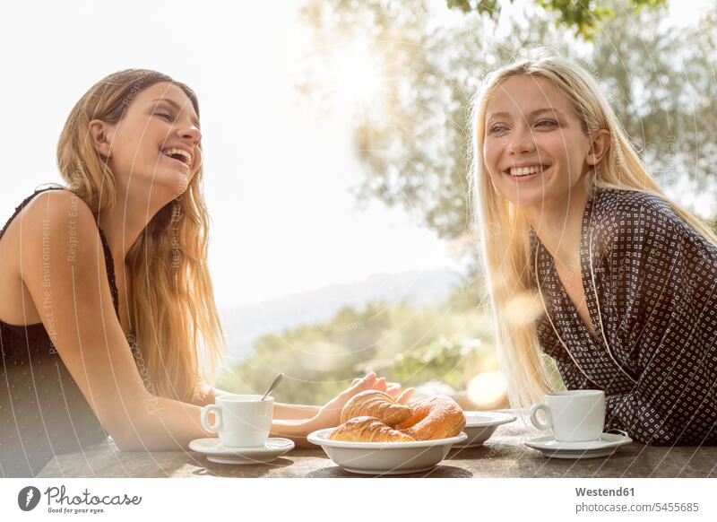 Zwei lachende Freunde am Frühstückstisch am Morgen Freundinnen Freundschaft Kameradschaft trinken Portrait Porträts Portraits Frau weiblich Frauen frühstücken