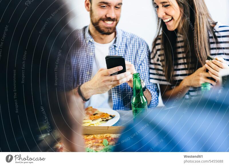Glückliches Paar teilt sich ein Handy am Esstisch Mobiltelefon Handies Handys Mobiltelefone Pärchen Paare Partnerschaft essen essend Tisch Tische Telefon