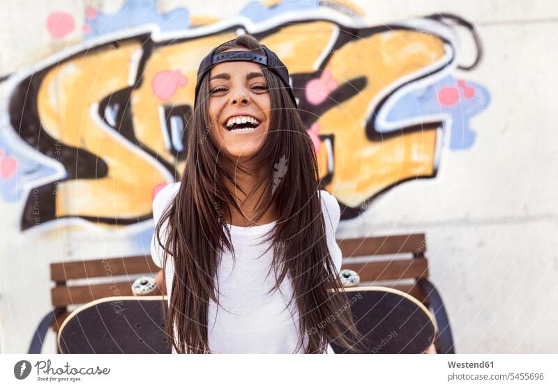 Lachende junge Frau mit Skateboard lachen weiblich Frauen Rollbretter Skateboards positiv Emotion Gefühl Empfindung Emotionen Gefühle fühlen Empfindungen