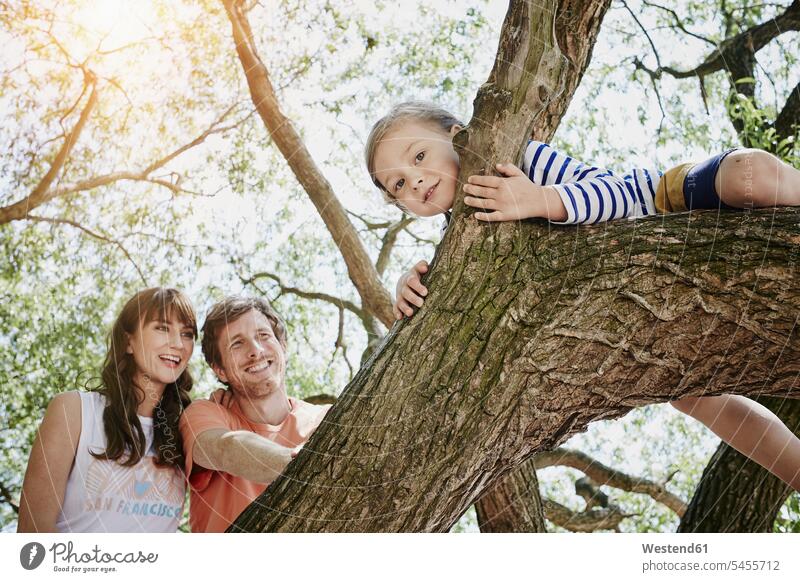 Eltern beobachten Tochter beim Klettern auf einem Baum lächeln klettern steigen Bäume Baeume Familie Familien Mensch Menschen Leute People Personen zusehen